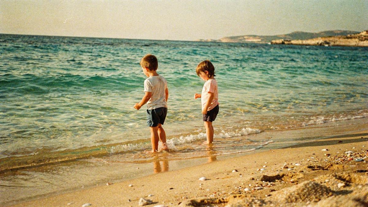 Two children wading in shallow turquoise water at a sandy Antalya beach in the late afternoon